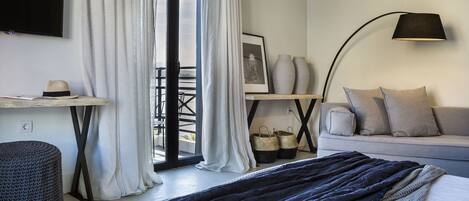 A modern bedroom with a bed, a desk, a sofa, and a balcony view.