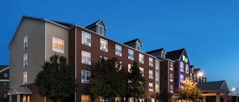 A multi-story hotel with a mix of brick and siding exteriors, multiple windows, and a well-maintained lawn.