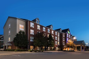 A multi-story hotel with a mix of brick and siding exteriors, multiple windows, and a well-maintained lawn.