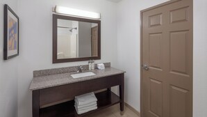 Un baño con tocador de madera oscura, un espejo grande y una puerta.