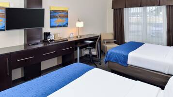 A hotel room with a bed, desk, chair, television, and artwork on the wall.