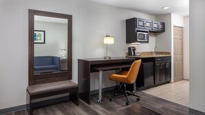 Una habitación de hotel moderna con un escritorio, una silla y un espejo grande.