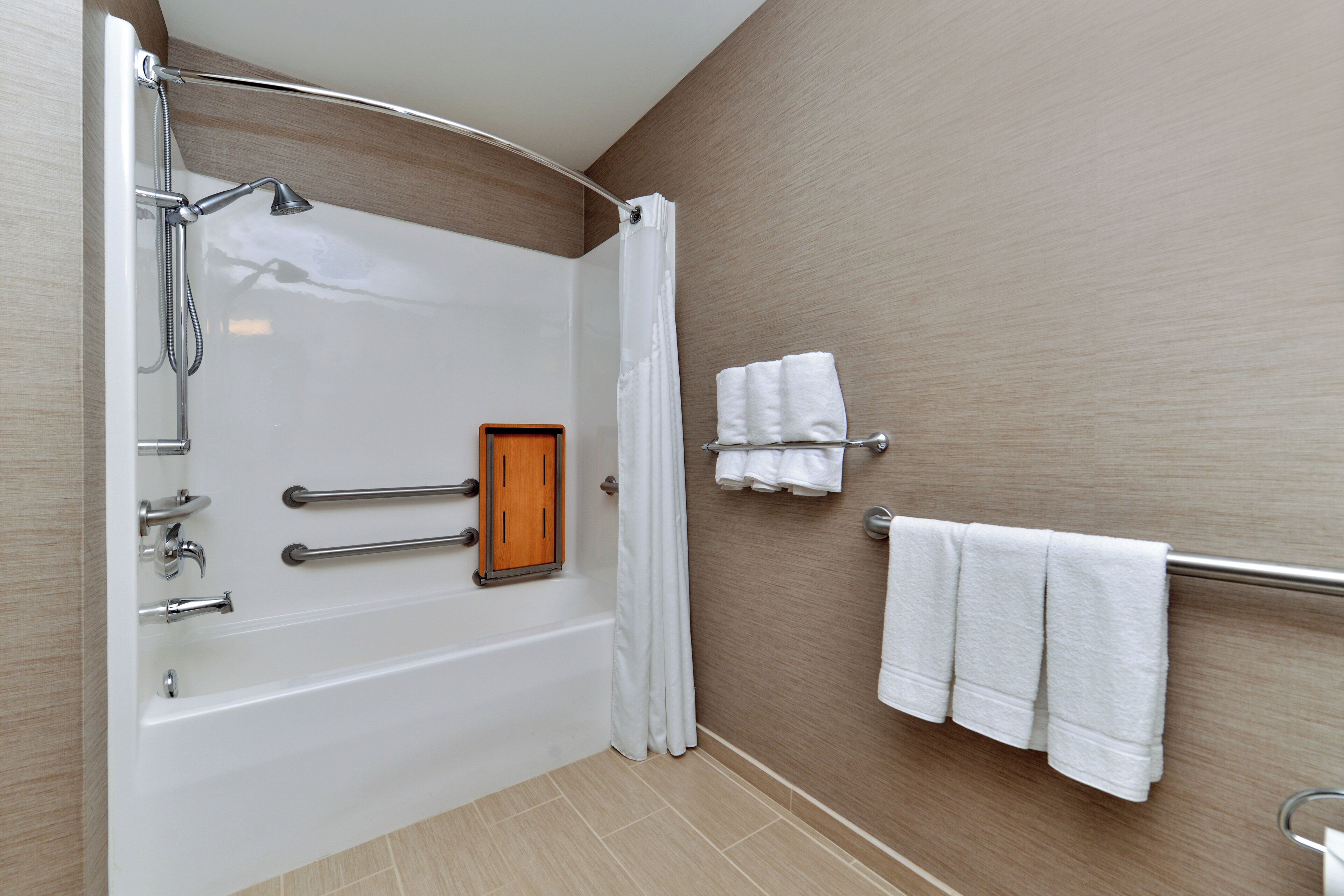 A bathroom with a bathtub, a shower, a towel rack, and a wooden panel.