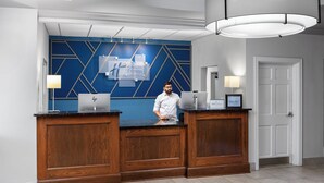 Un mostrador de recepción con diseño moderno, con una pared azul de motivos geométricos y detalles de madera.