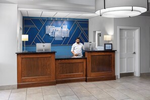 Uma receção com design moderno, destacando uma parede azul geométrica e acabamento em madeira.