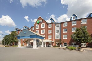 Un hôtel Holiday Inn Express avec une façade en briques, une entrée abritée et un ciel dégagé.