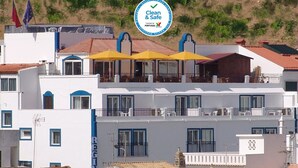 Un hôtel doté de nombreux balcons, dont certains sont ornés de parasols jaunes, et affichant un panneau indiquant qu’il respecte les normes « propreté et sécurité ».