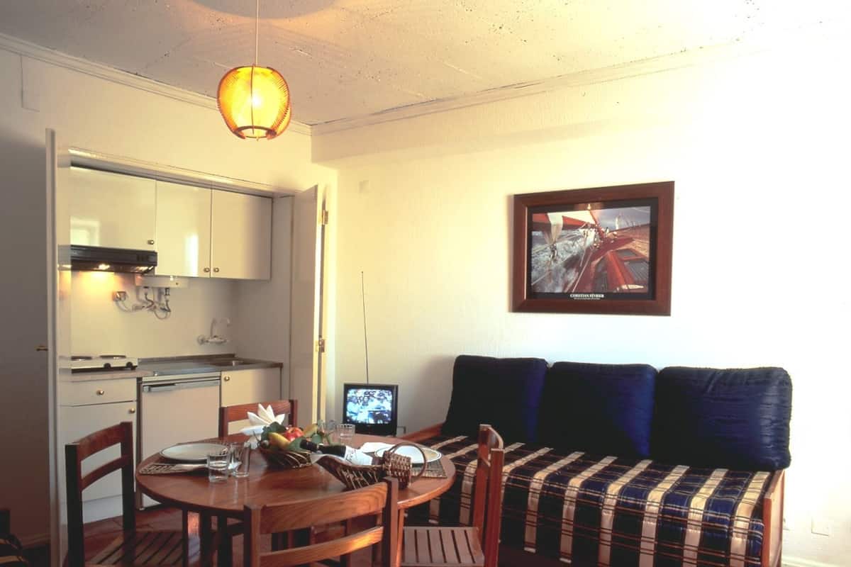 Un espacio habitable compacto con una mesa de comedor, sillas, un sofá y un televisor.