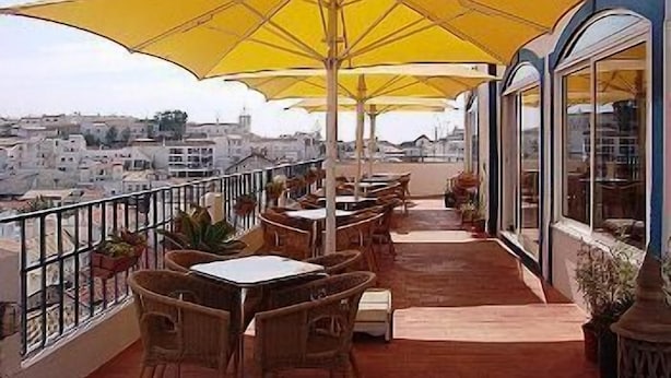 Une terrasse avec des sièges extérieurs, des parasols jaunes et une vue sur le paysage urbain.