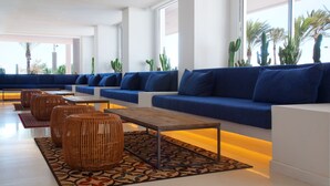 Ein stilvoller Lounge-Bereich mit blauen Sofas, Korpus-Ottomanen und einem gemusterten Teppich.