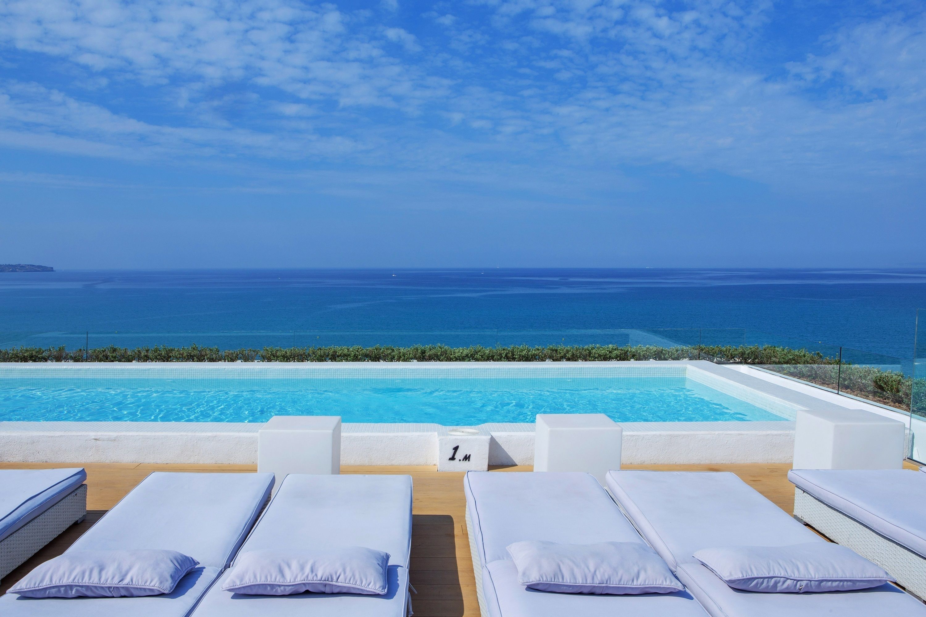 A poolside area with lounge chairs and a view of the ocean.