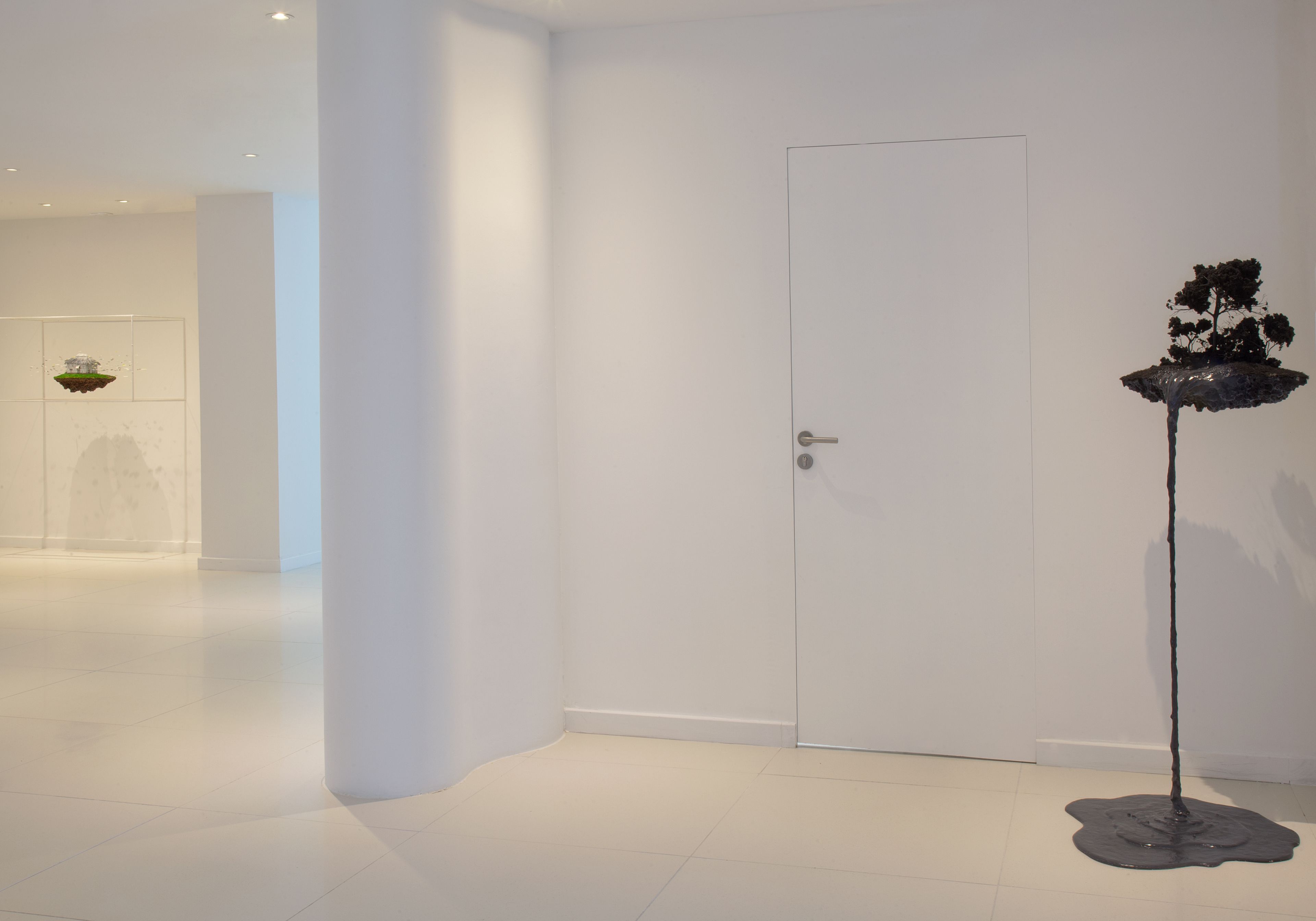 A minimalist room with a white door, a floor lamp, and a wall-mounted light fixture.