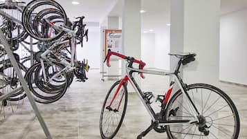 Zona de alquiler de bicicletas con varias bicicletas y un cartel que dice 'Hotel Tropic Max Hurzeler'.