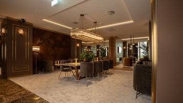 A modern dining area with a marble floor, a large chandelier, and a seating arrangement.