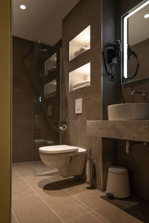 A modern bathroom with a glass-enclosed shower, a toilet, a sink, and a mirror. - Art Hotel Rotterdam (Rotterdam)