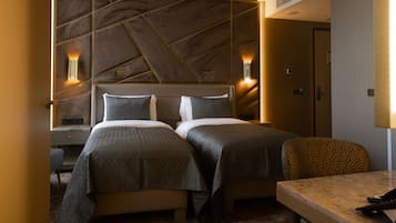 Una camera d'albergo con due letti, una scrivania e una testiera a motivi decorativi.