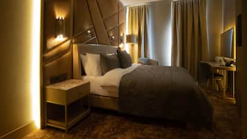 Et moderne hotelværelse med en stor seng, et natbord med lampe, et skrivebord med stol og et stort spejl.