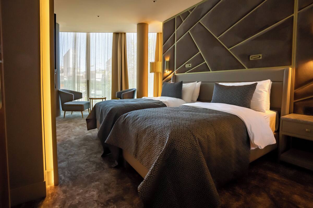 A hotel room with a large bed, a desk, and a chair.