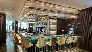 A bar area with a curved counter, bar stools, and a decorative ceiling light fixture. - Art Hotel Rotterdam (Rotterdam)