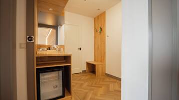 A compact hotel room with a kitchenette, a small refrigerator, and a wooden floor.