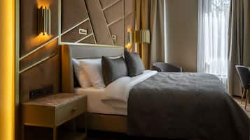 Una camera d'albergo moderna con un letto grande, un comodino, una sedia e un lampadario a parete.
