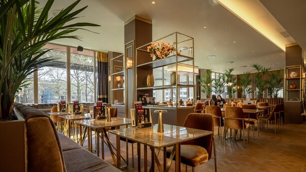 A modern restaurant with high ceilings, large windows, and a variety of seating options including tables and sofas. - Art Hotel Rotterdam (Rotterdam)