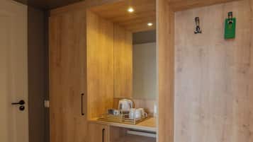 Eine kleine Küche mit Holzschränken, einem integrierten Minikühlschrank und einer Mikrowelle.