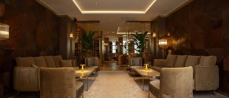 Een ruime lobby met een modern design, met een centraal zithoek met banken en fauteuils, een gestreept wand en een vloerbedekking.