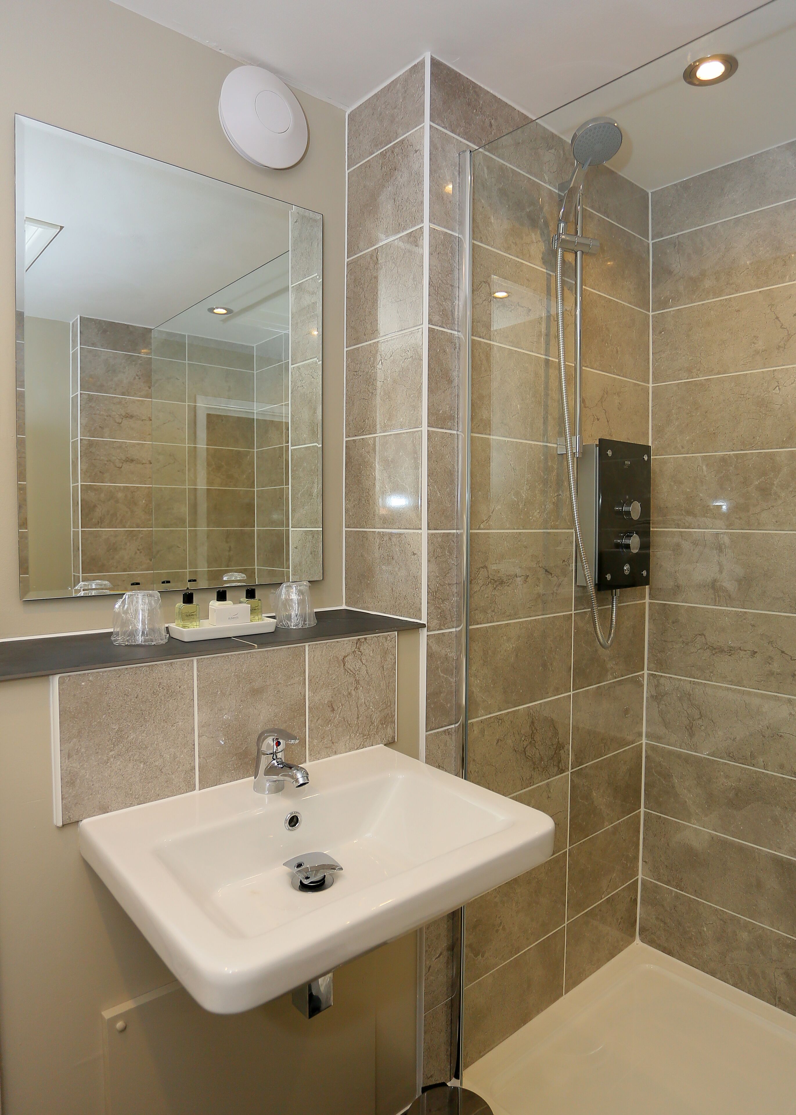 Un baño moderno con un espejo grande, un lavabo y una zona de ducha.