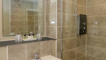 Un baño moderno con un espejo grande, un lavabo y una zona de ducha.