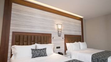 A hotel room with two beds, a wooden headboard, a marble wall, and a wall-mounted light fixture.