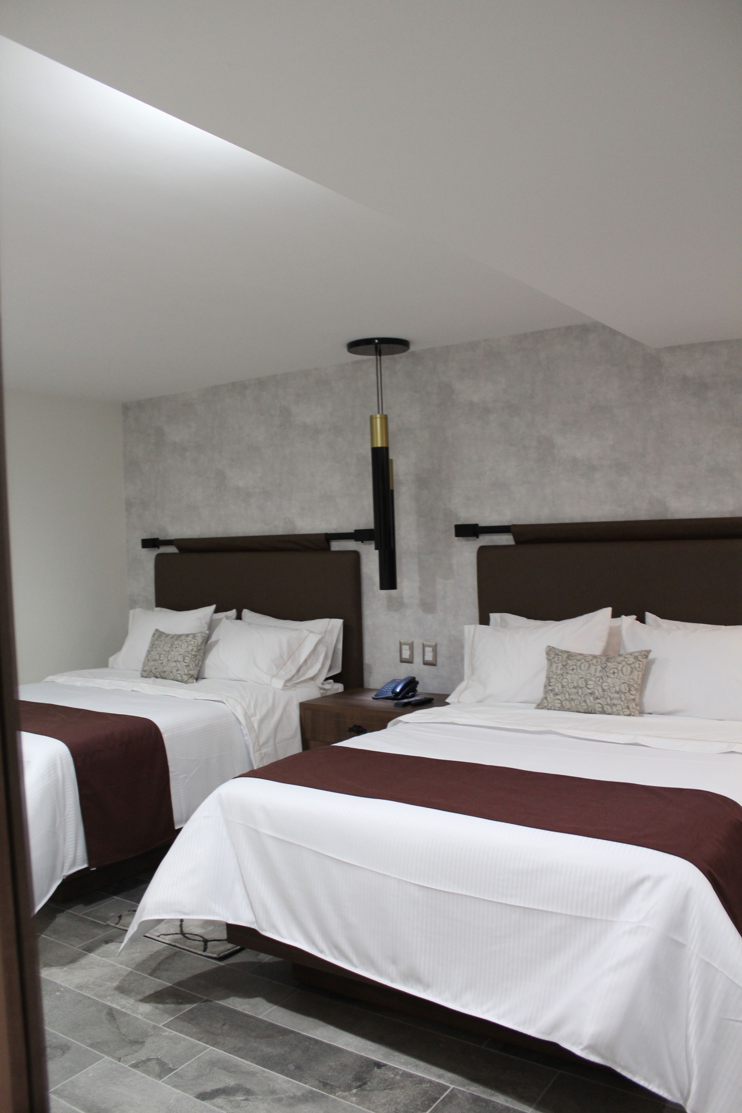Ein Hotelzimmer mit zwei Betten, modernem Design, einem Telefon und einem Nachttisch.