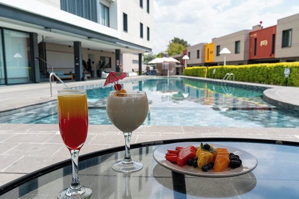 Una piscina al aire libre, sombrillas, sillones reclinables de piscina