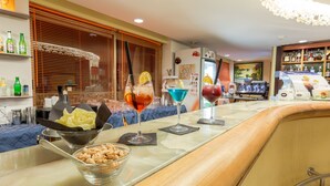 A bar area with a variety of drinks, a bowl of nuts, and a refrigerator with a decorative item on top. - Paradise Beach Resort (Castelvetrano)