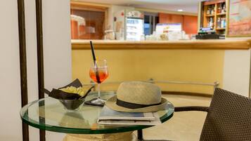 A glass table with a drink, a hat, and a bowl of chips.