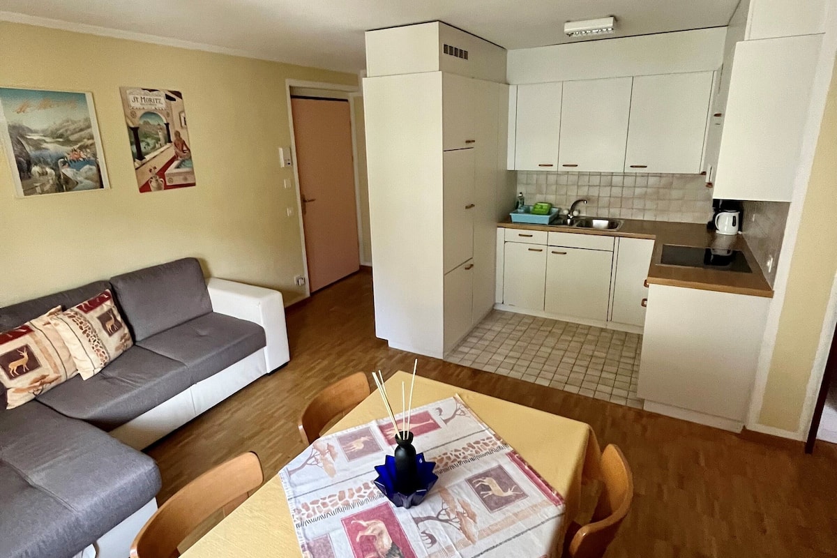 A compact living space with a sofa, dining table, and kitchenette.