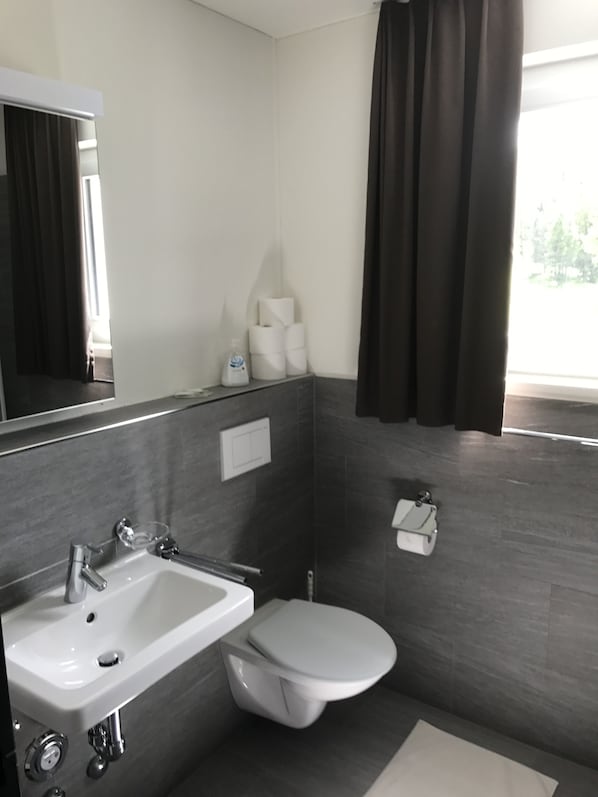 Un baño moderno con lavamanos, inodoro y espejo.