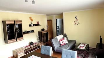Una sala de estar moderna con comedor, que incluye una mesa de madera, sillas y un sofá con cojines decorativos.