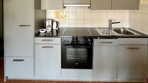 Una cocina moderna con armarios grises, horno empotrado, pileta y cafetera.