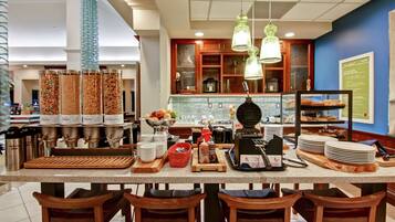 A breakfast bar with a coffee machine, a fruit bowl, and various condiments.