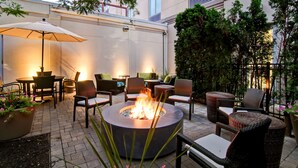 An outdoor patio with a fire pit, wicker furniture, and potted plants. - Hilton Garden Inn Toronto/Burlington (Burlington)