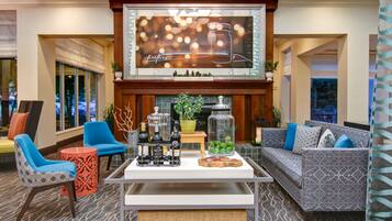 A lobby area with seating, a fireplace, and a television screen displaying a wine advertisement.