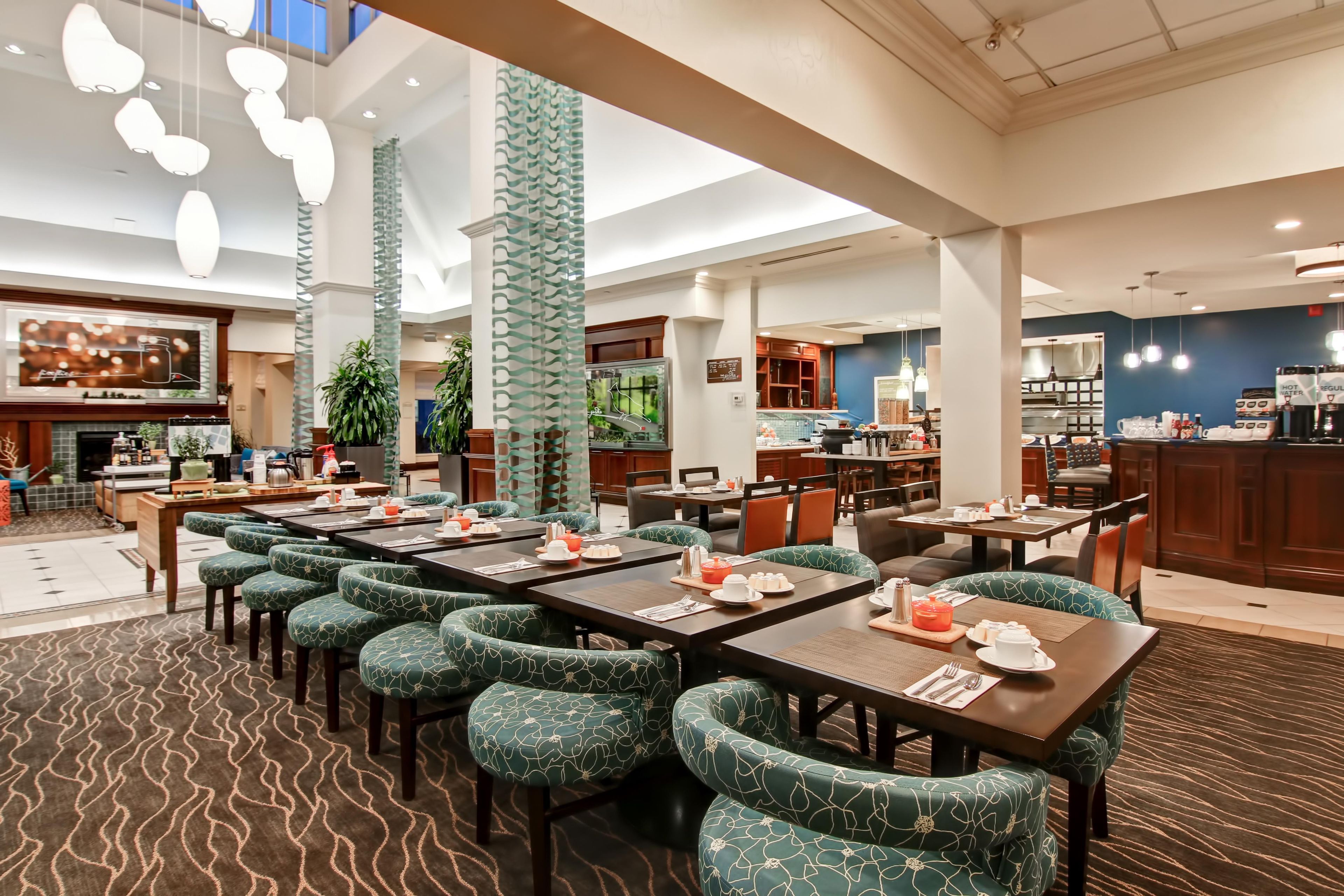 Un comedor de hotel con varias mesas y sillas, un bar y una cocina al fondo.