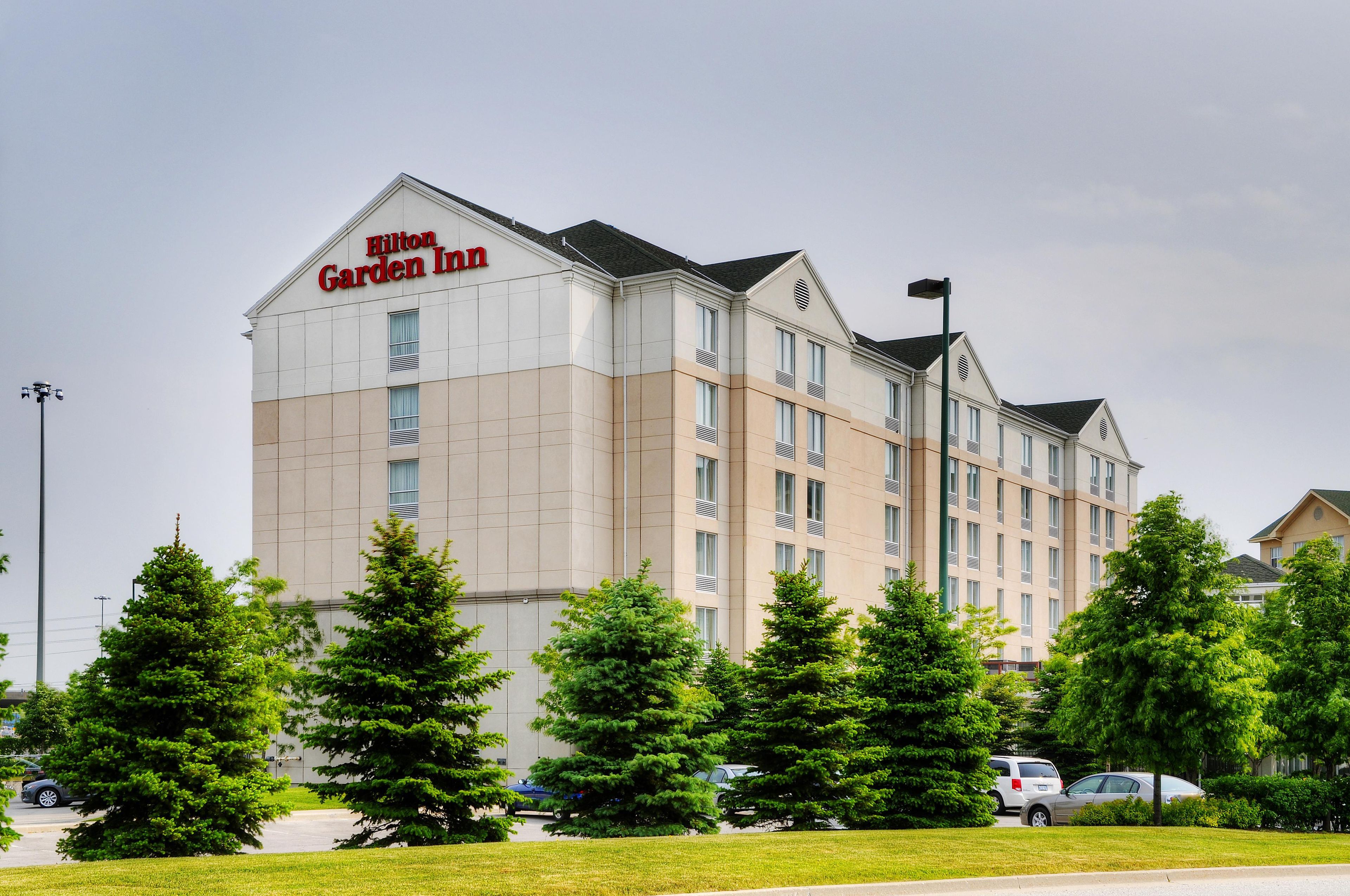 Un hôtel Hilton Garden Inn à plusieurs étages, avec une façade beige, de grandes fenêtres et un toit plat.