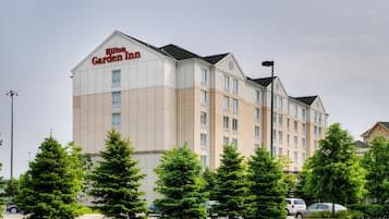 Un hôtel Hilton Garden Inn à plusieurs étages, avec une façade beige, de grandes fenêtres et un toit plat.