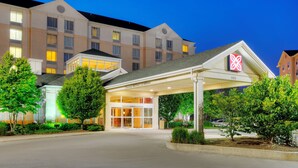 A hotel entrance with a covered driveway, a clear sky, and a large building in the background. - Hilton Garden Inn Toronto/Burlington (Burlington)