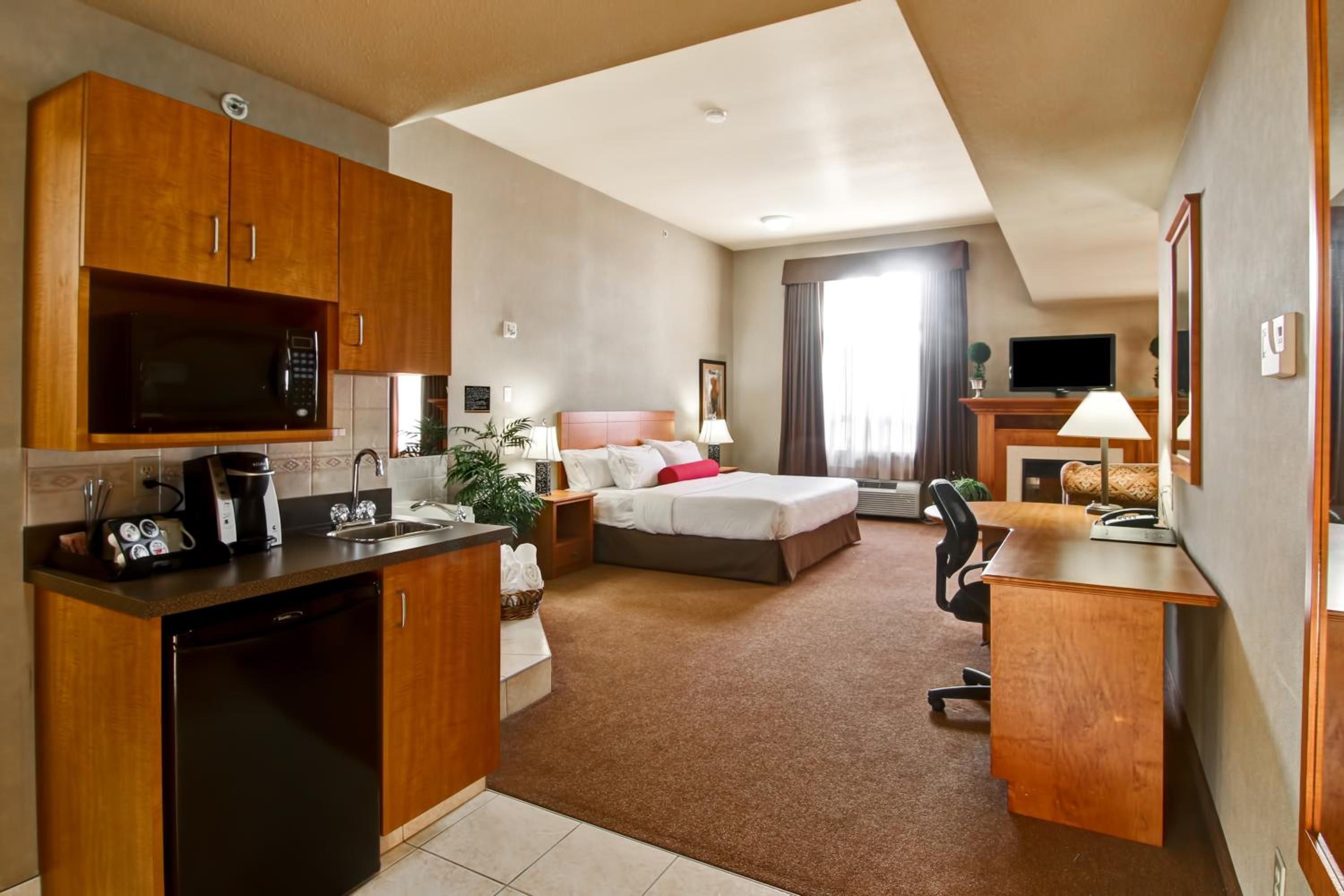 Una habitación de hotel con kitchenette, cama, escritorio y televisión.