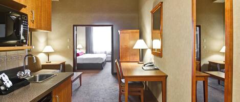Una habitación de hotel con kitchenette, una cama, un escritorio y un espejo.