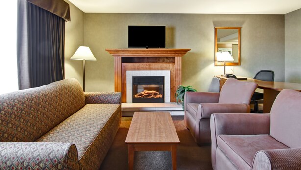A hotel room with a fireplace, a sofa, a coffee table, and a desk with a chair. - Canalta Hotel Provost (Provost)