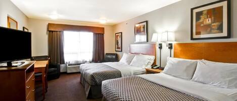 A hotel room with two beds, a desk, a television, and a window with curtains.